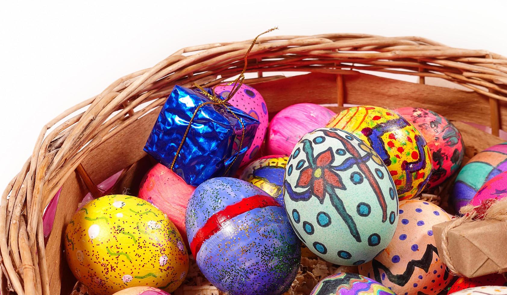 Coloridos huevos de pascua y caja de regalo en una canasta de madera foto