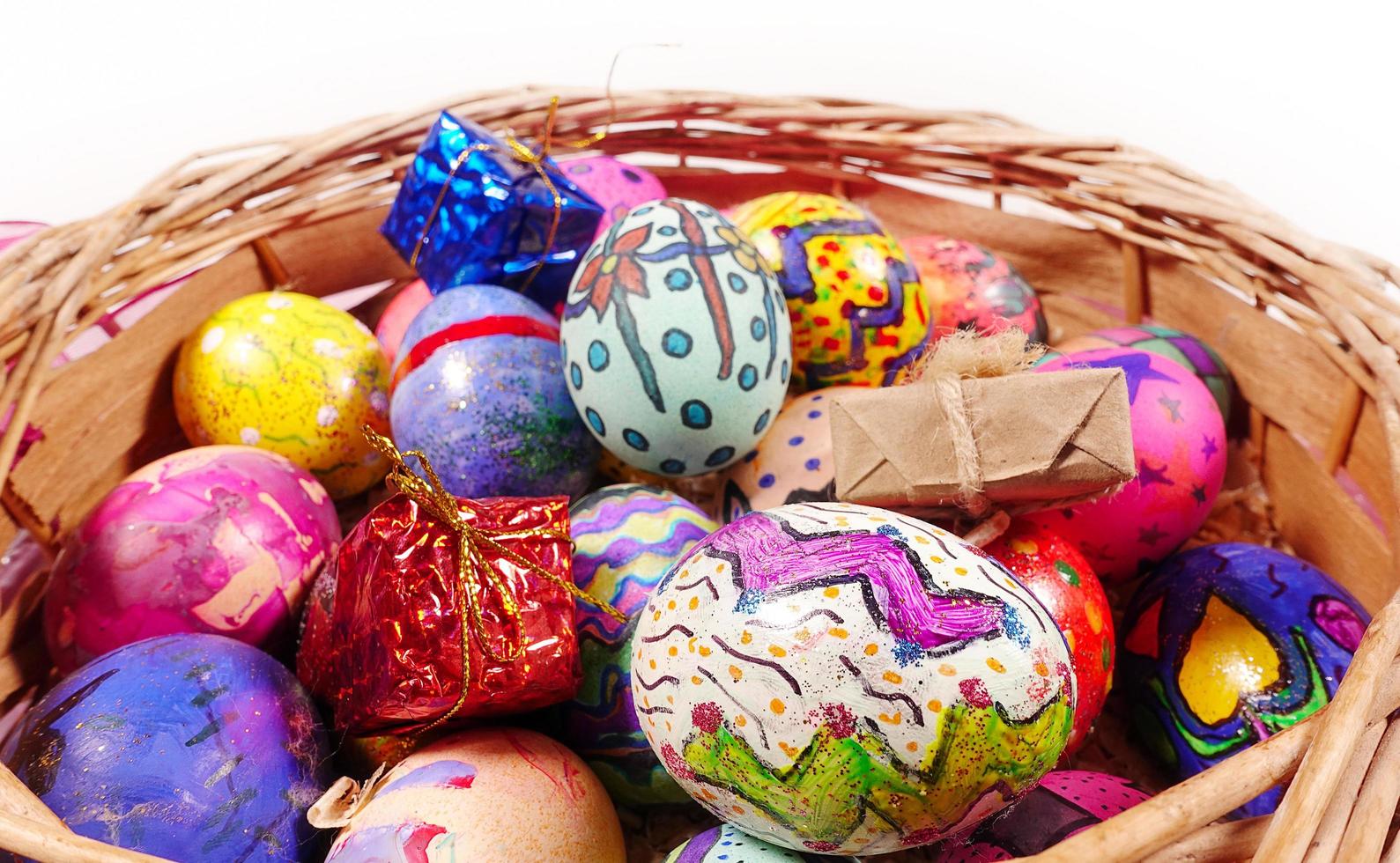 Coloridos huevos de pascua y caja de regalo en una canasta de madera foto