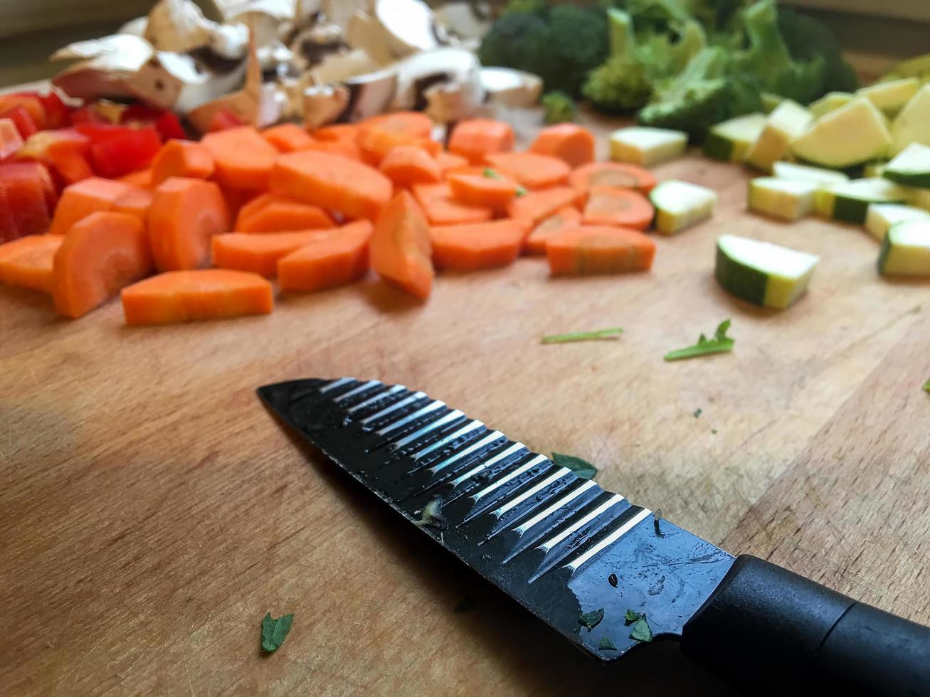 Cuchillo de zanahoria picada y champiñones en la mesa de la cocina foto