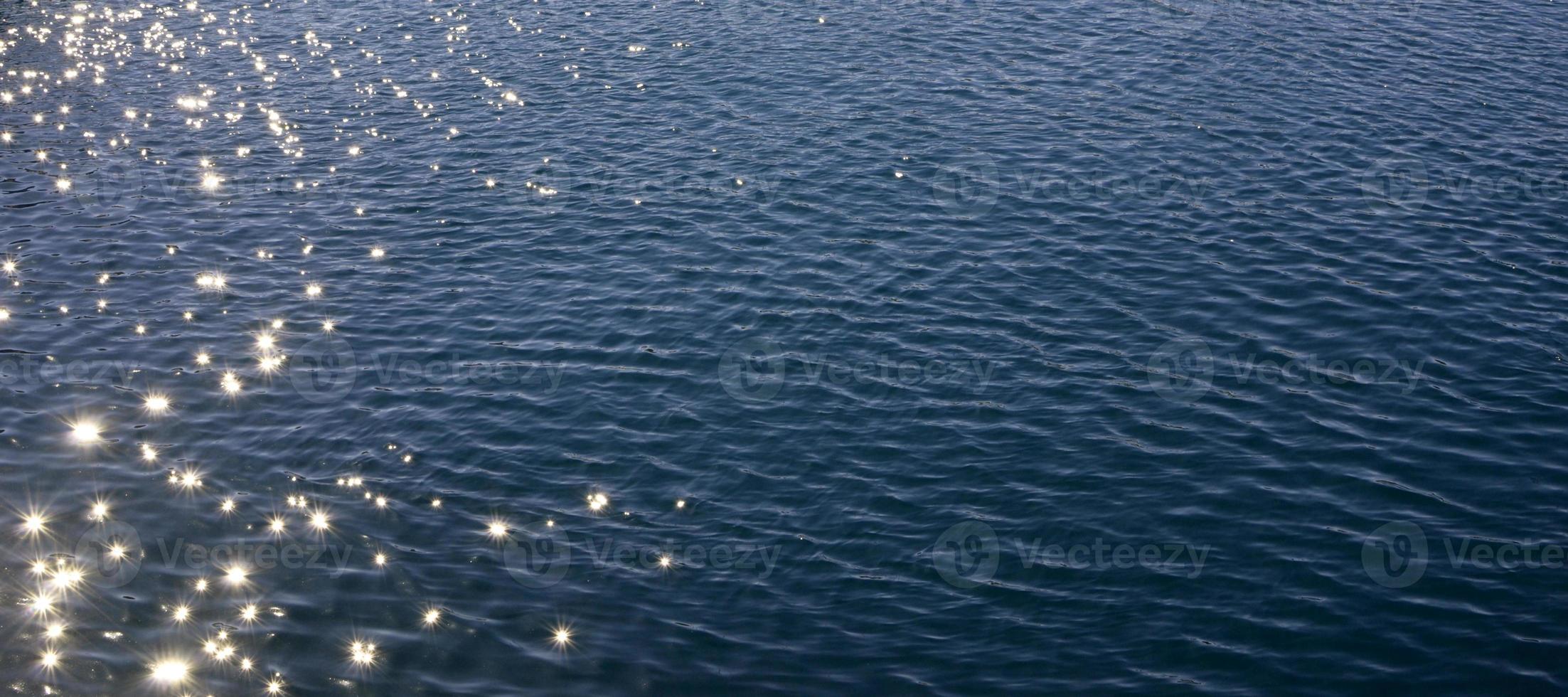 Superficie del agua de mar azul con ondas y reflejos del sol. foto