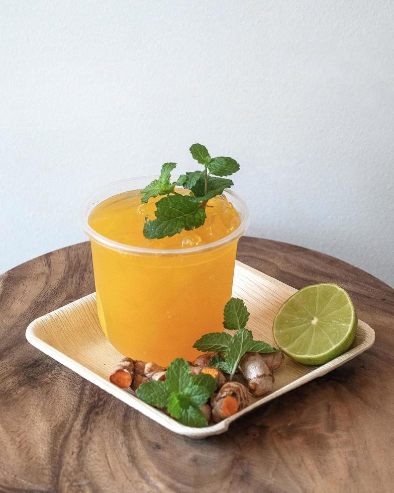 Jugo de cúrcuma con hielo aislado en bandeja de madera foto