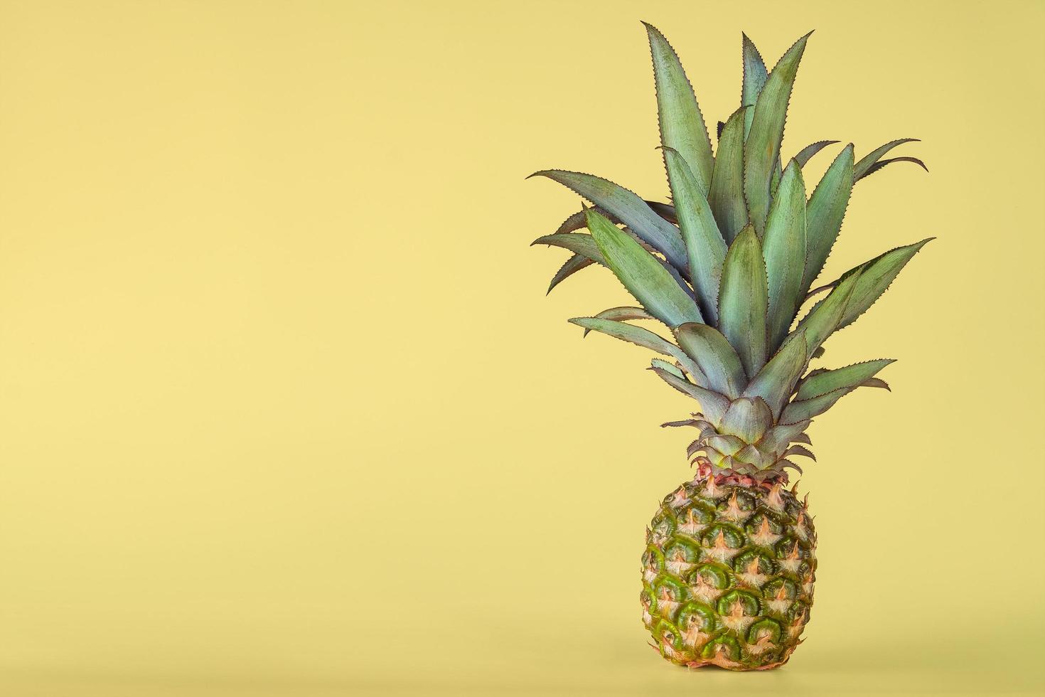 Pineapple fruit isolated on yellow background. photo