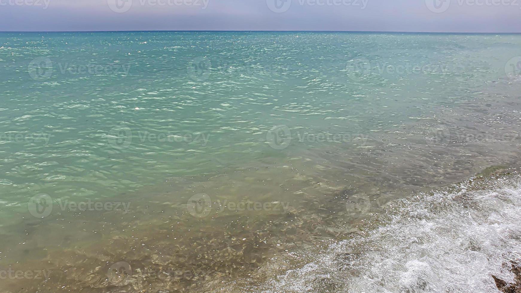 Seascape. Azure color of water, waves foaming on the shore. photo