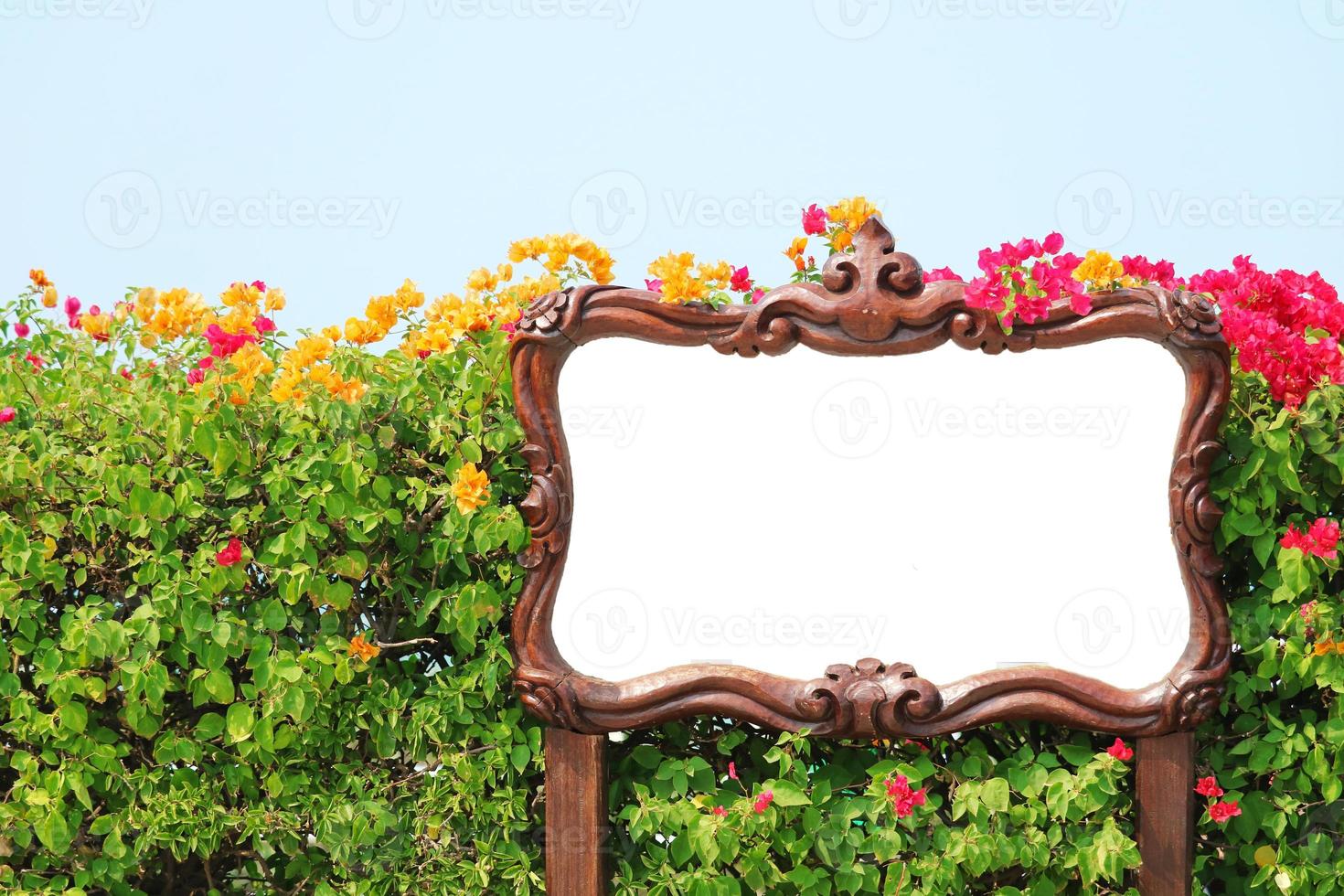 Sign with white background and wooden frame in front of garden photo