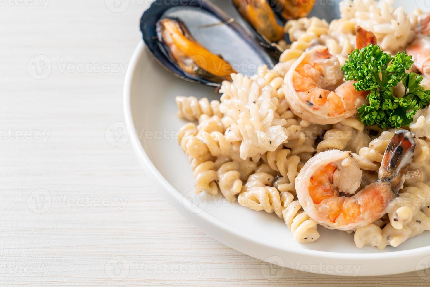 Pasta espiral con salsa de crema de champiñones y mariscos - estilo de comida italiana foto