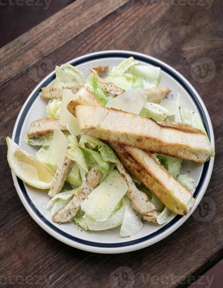 Simple healthy organic chicken caesar salad on wood table photo
