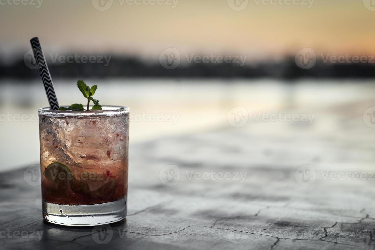 Strawberry caipirinha mixed cocktail drink in riverside Vientiane Laos outdoor bar at sunset photo