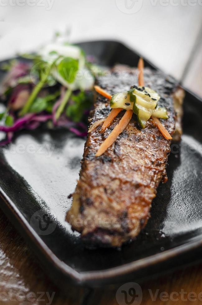 Marinated grilled barbecue pork rib with salad and pickled vegetables photo