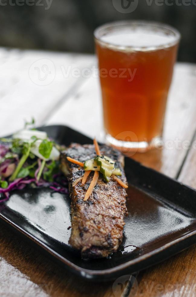 Costilla de cerdo asada a la parrilla adobada con ensalada y verduras en escabeche con cóctel michelada foto