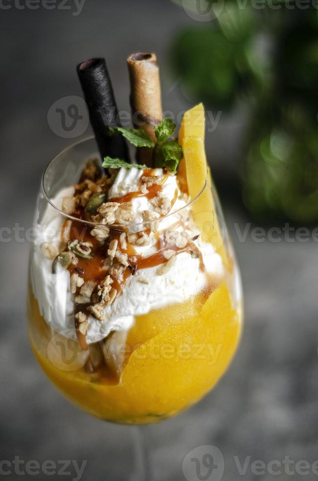 Sundae de helado tropical de mango orgánico y maracuyá en copa de vino foto