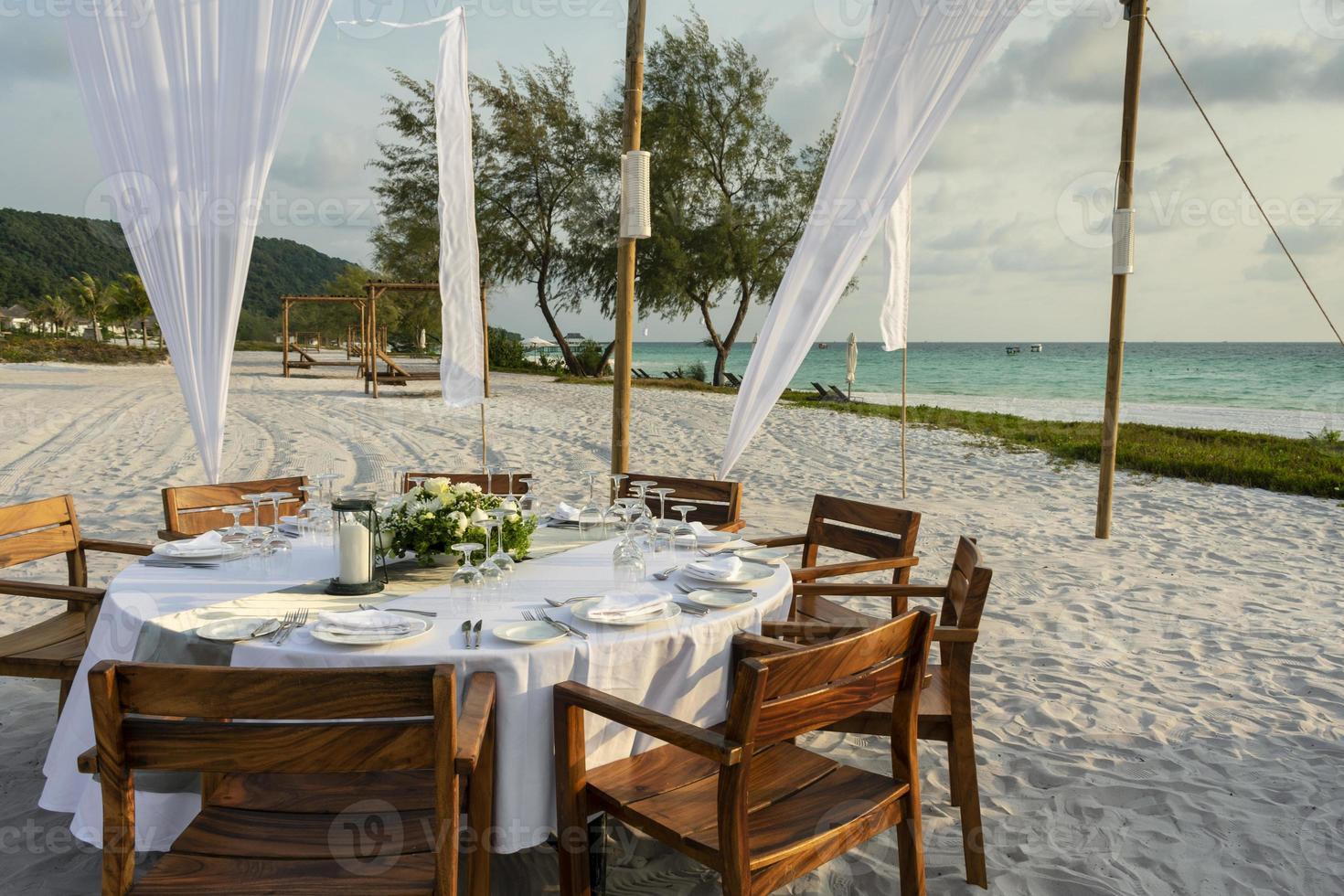 Diseño de mesa de boda romántica al atardecer afuera en la playa tropical asiática en Bali, Indonesia foto