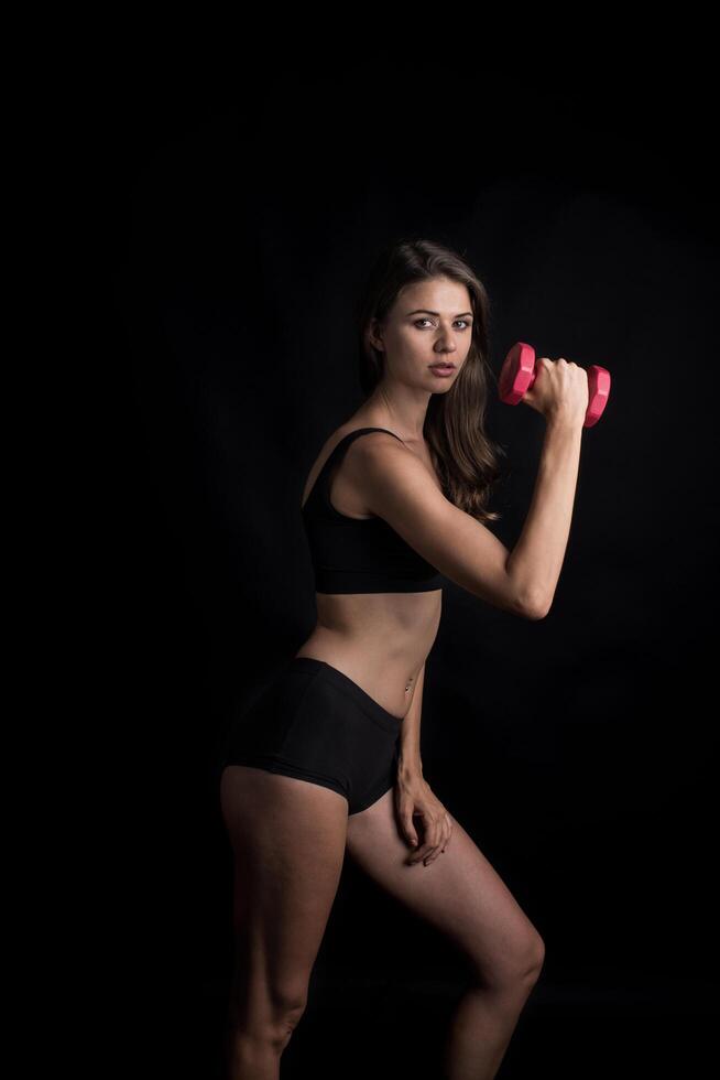 Young beautiful woman making physical exercises with dumbbells. photo