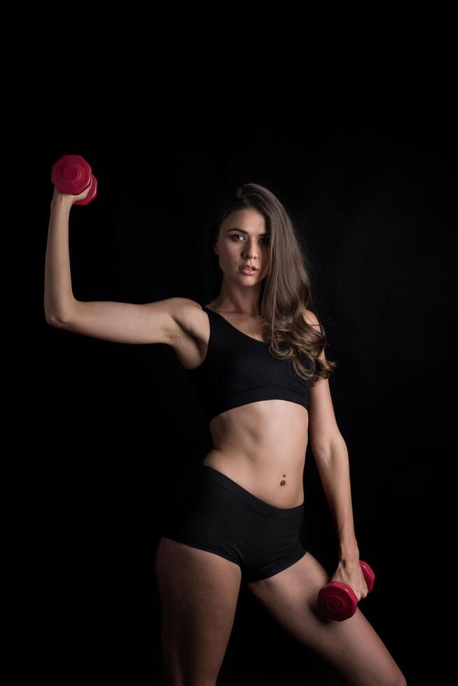 Young beautiful woman making physical exercises with dumbbells. photo