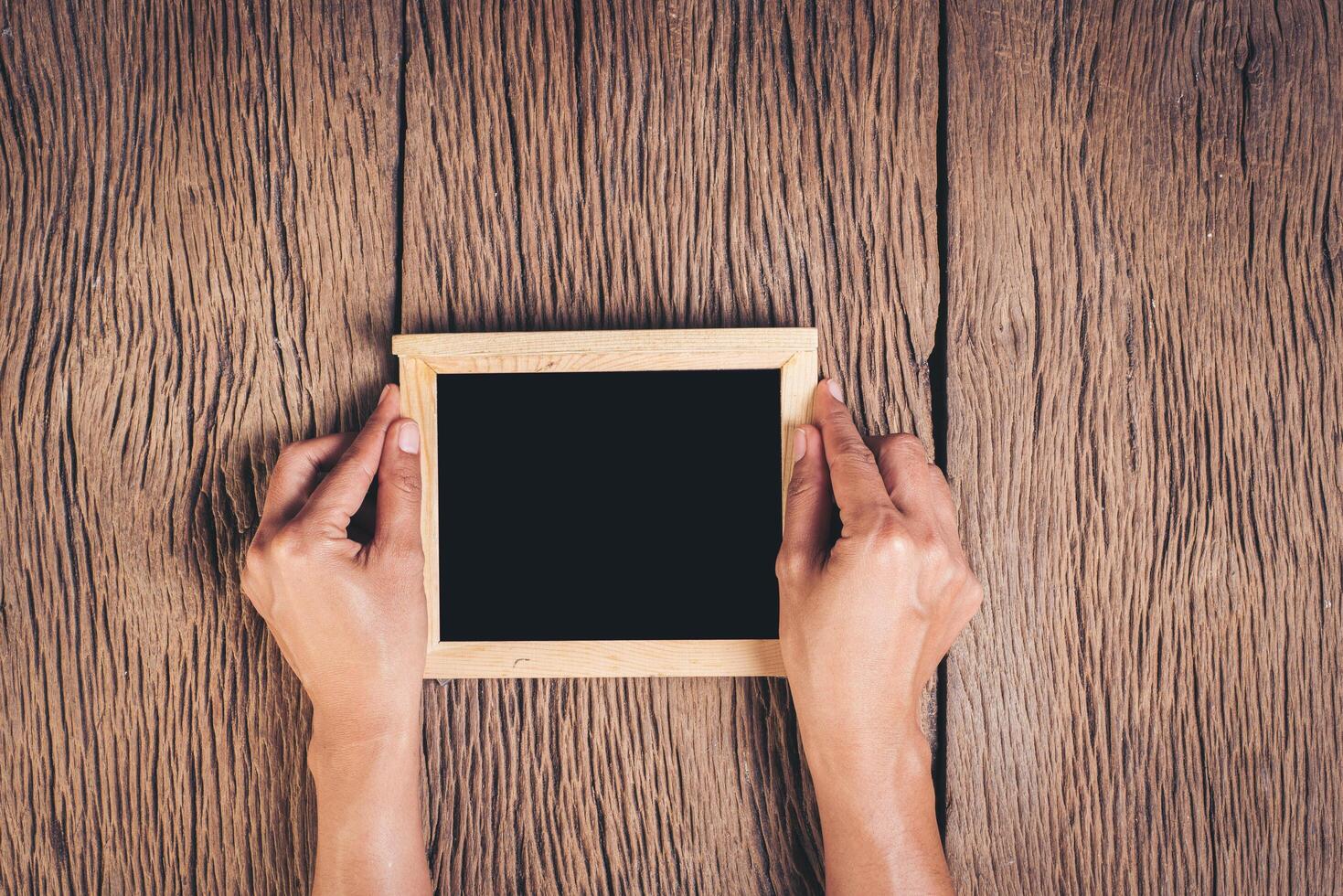 Top view Hand holding chalkboard  on wood background. photo