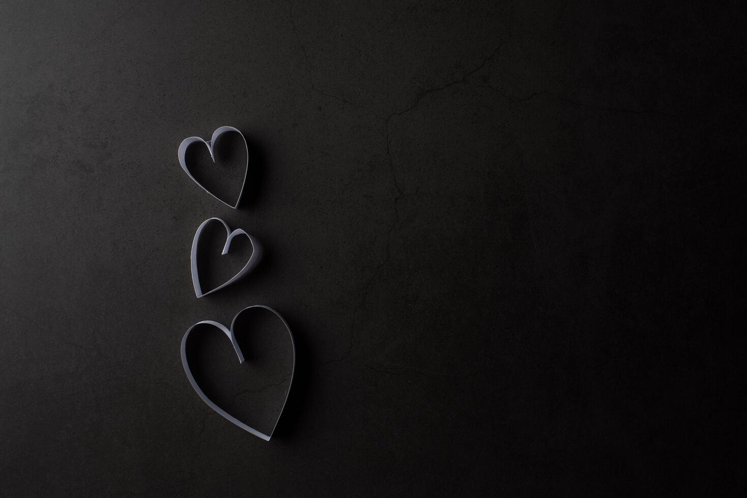 White heart shaped paper in shadow on black background. photo