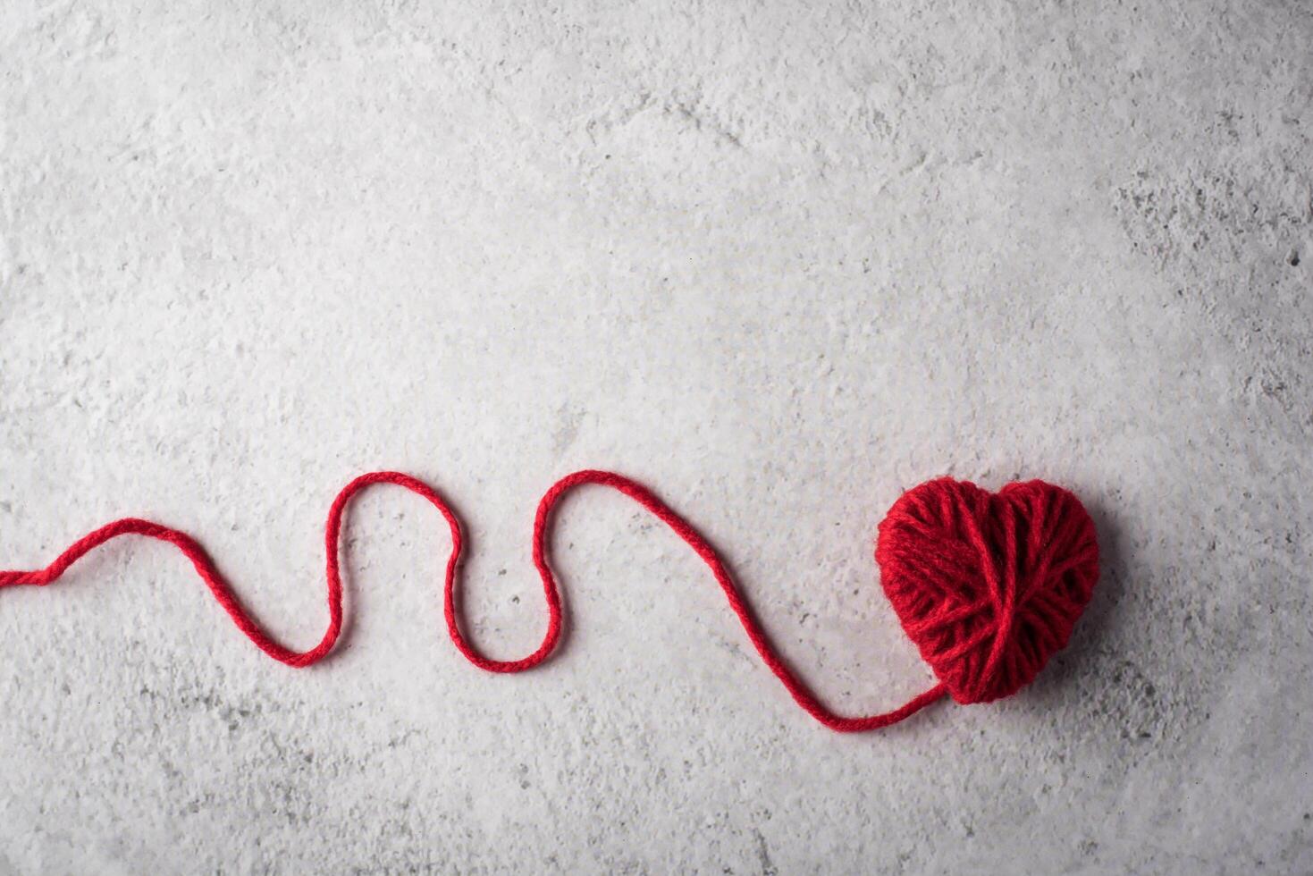Red yarn heart shaped on the wall background. photo