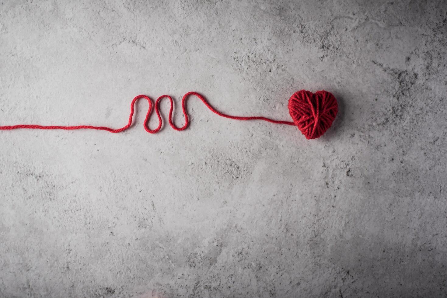 Red yarn heart shaped on the wall background. photo