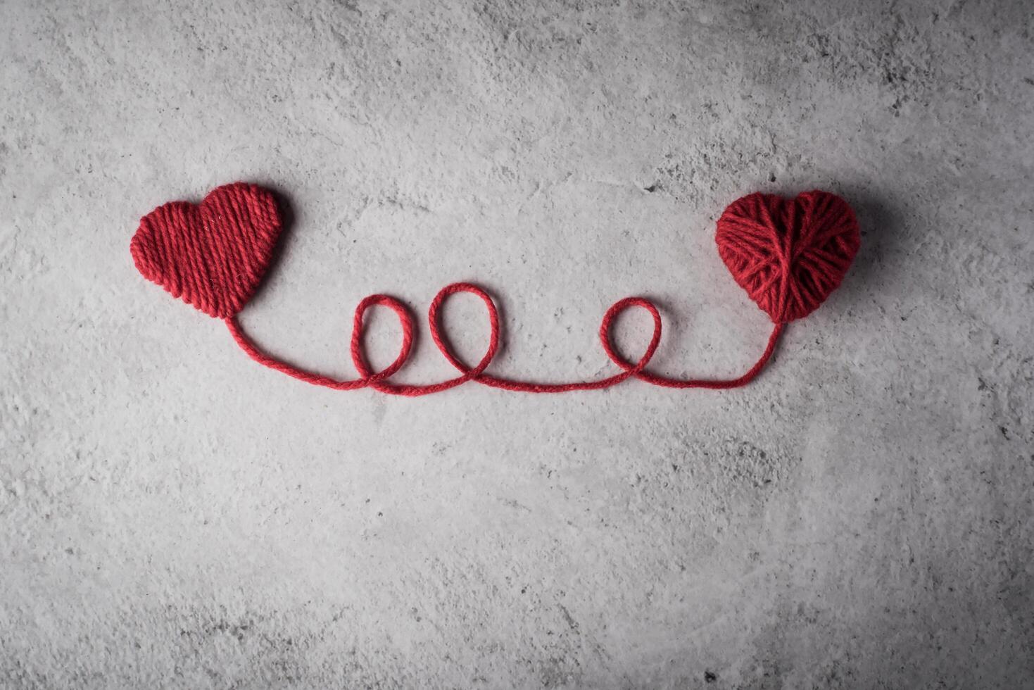 Red yarn heart shaped on the wall background. photo