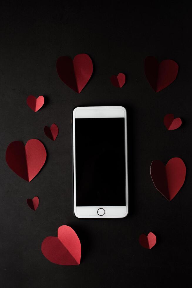 Heart and phone on black wall background. photo