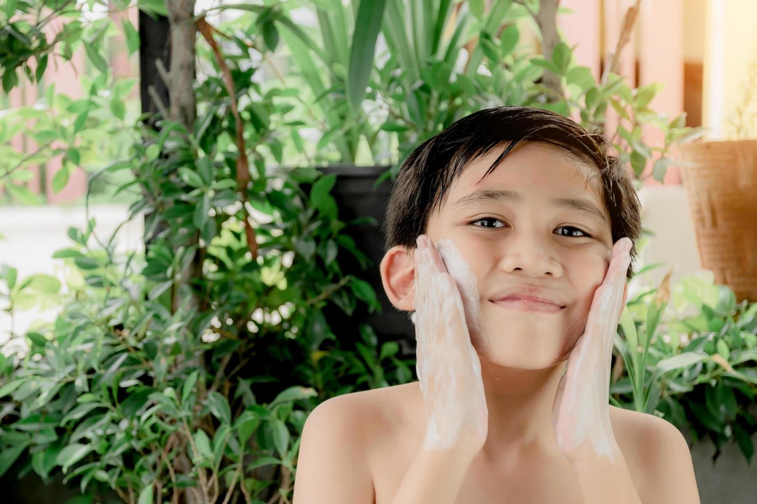 lindo adolescente asiático limpiando su cara con un limpiador espumoso foto