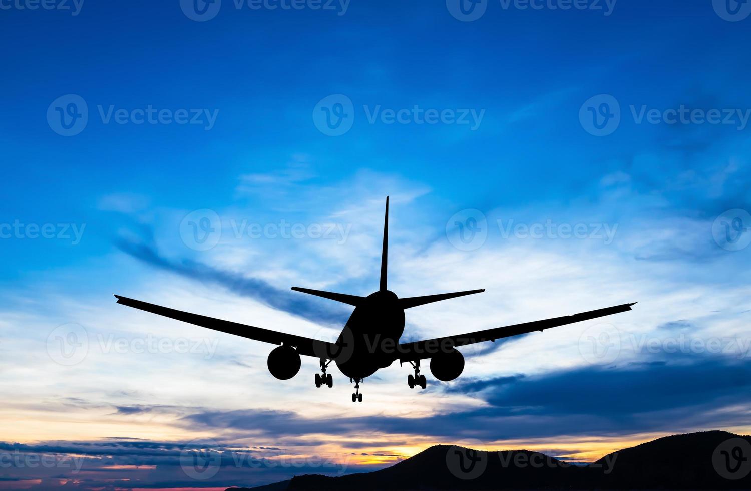 silueta de avión comercial volando al atardecer foto