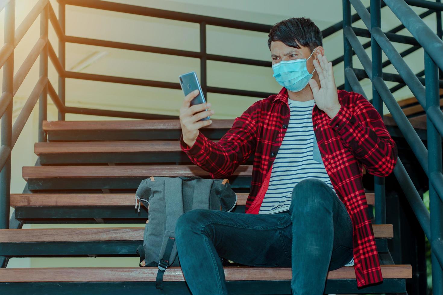 Hombre asiático haciendo videollamadas facetime con smartphone en casa foto