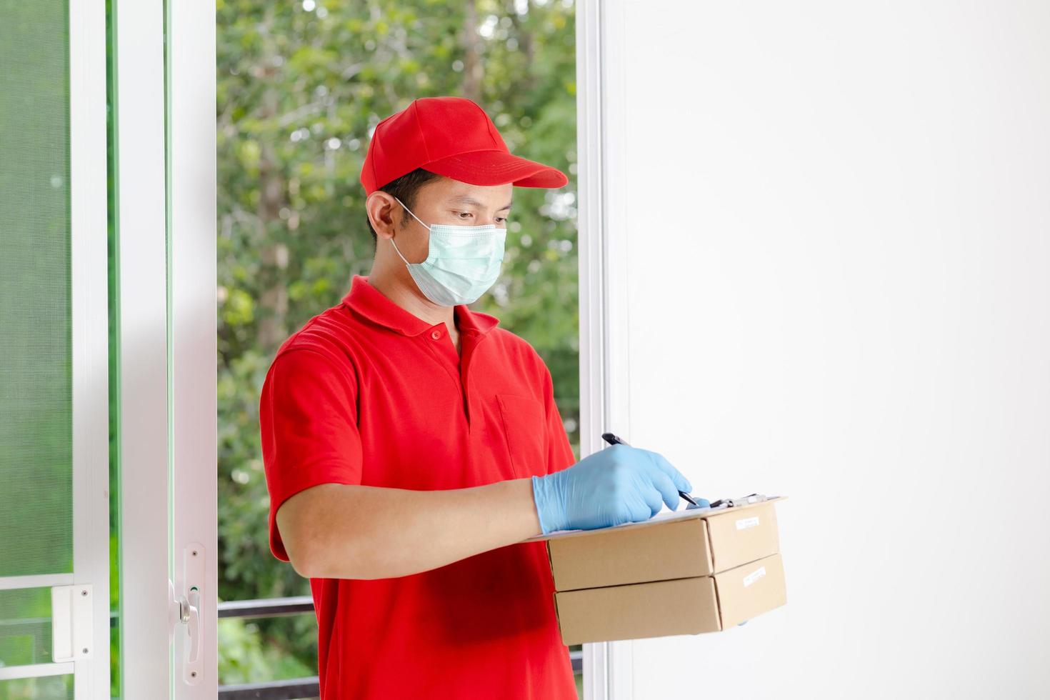 un repartidor vestido con una camisa roja y un sombrero sostiene una caja de paquetería foto