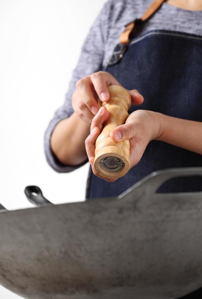 Chef grinding pepper to a stainless steel pan photo