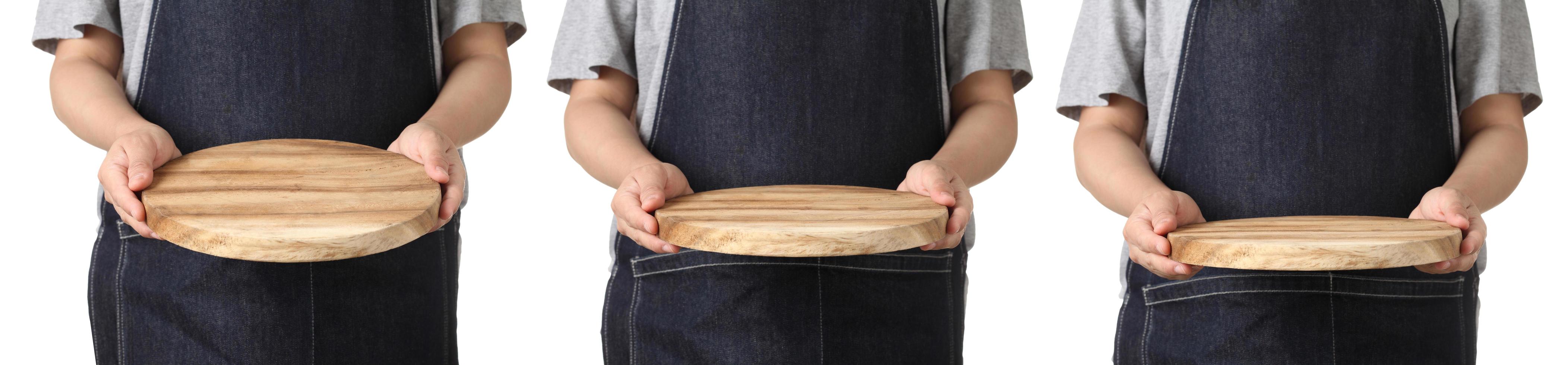 Chef sosteniendo tabla de cortar de madera sobre fondo blanco. foto
