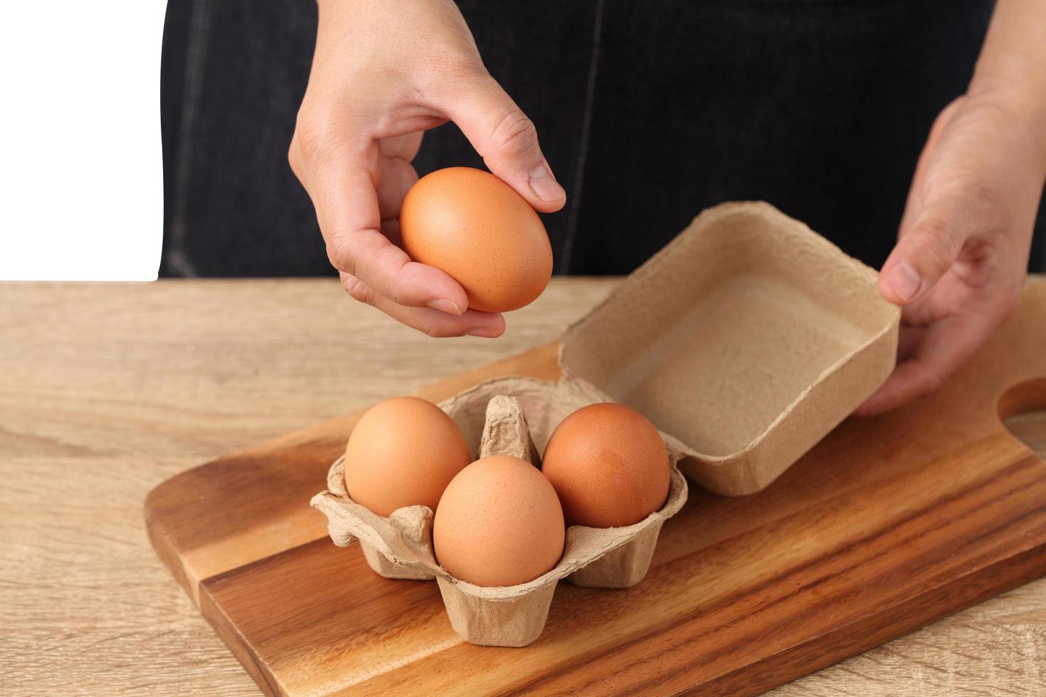 Mujer sosteniendo huevos de gallina en caja de cartón sobre fondo blanco. foto