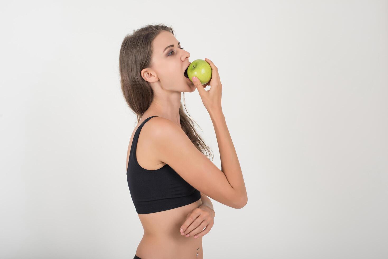 mujer de belleza sosteniendo manzana verde mientras aislados en blanco. foto