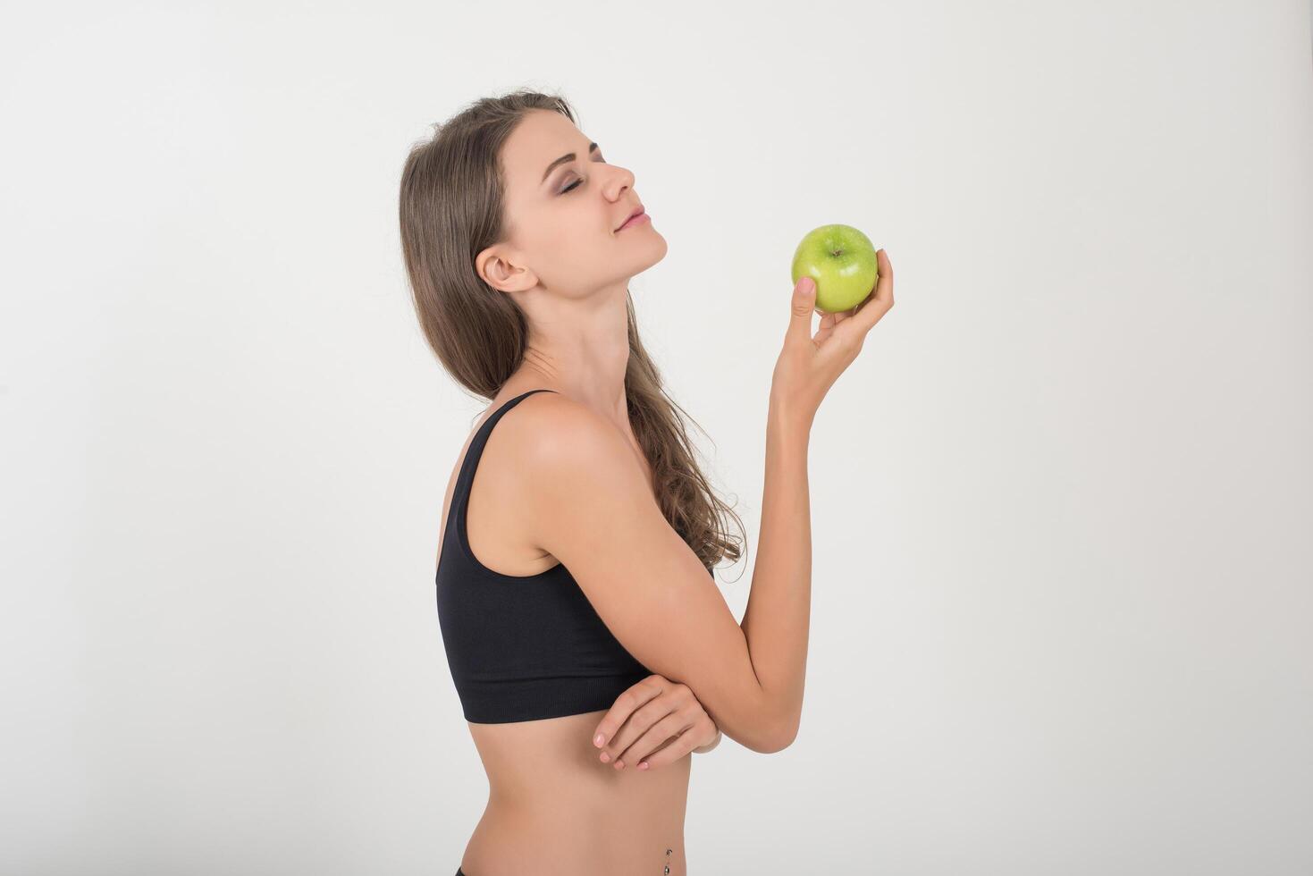 mujer de belleza sosteniendo manzana verde mientras aislados en blanco. foto