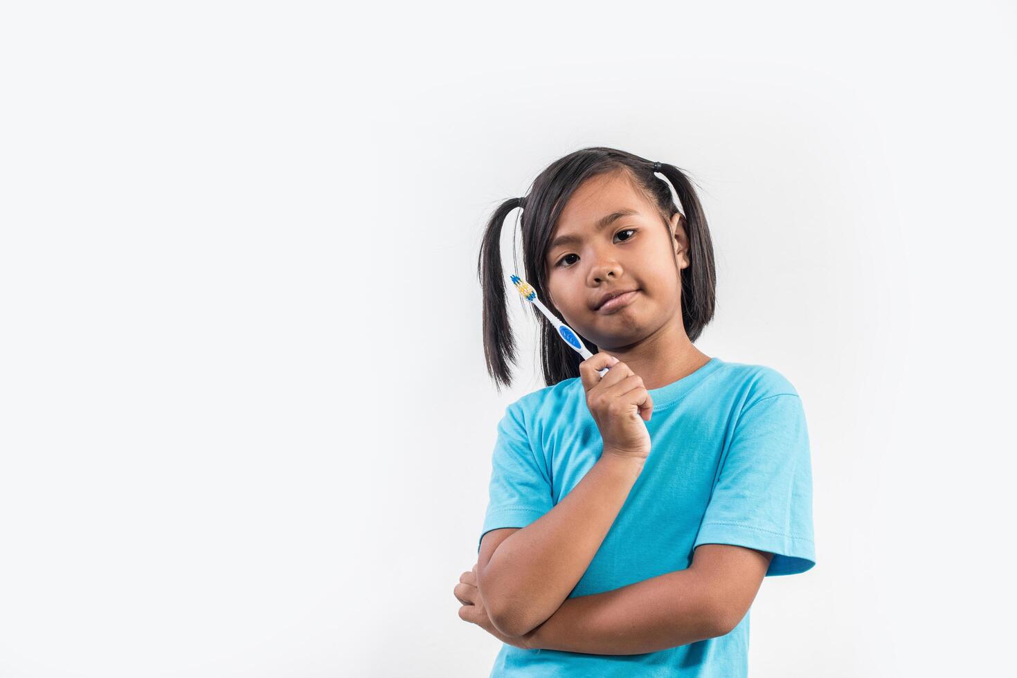 Little girl brushing her teeth in studio shot photo