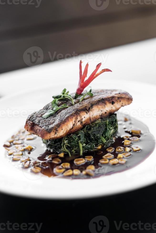 filete de salmón con espinacas al vapor y maíz con salsa dulce de soja y ostras foto