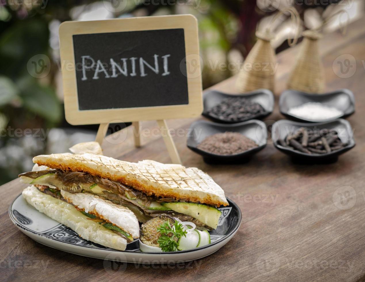 Vegano sándwich de panini tostado de verduras asadas en un jardín rústico ajuste de la tabla al aire libre en Sicilia foto