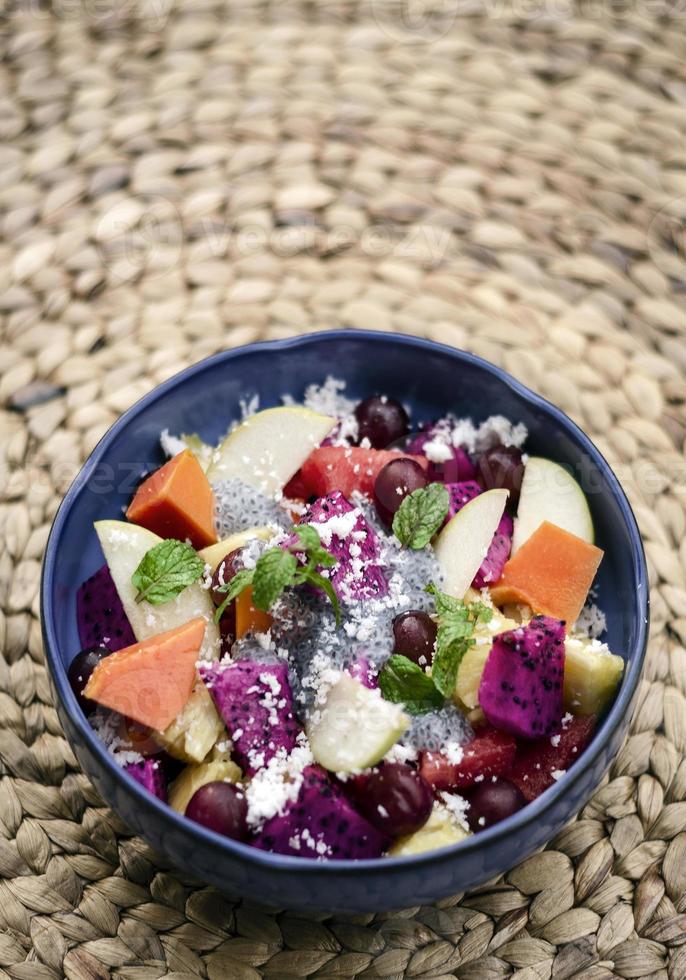 Exotic mixed tropical Asian fruit salad with basil seeds and coconut in bowl outdoors photo