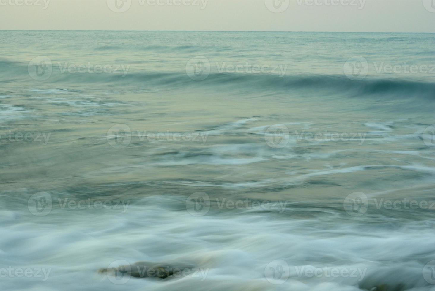 turbulencia de agua de mar y rocas en la costa foto