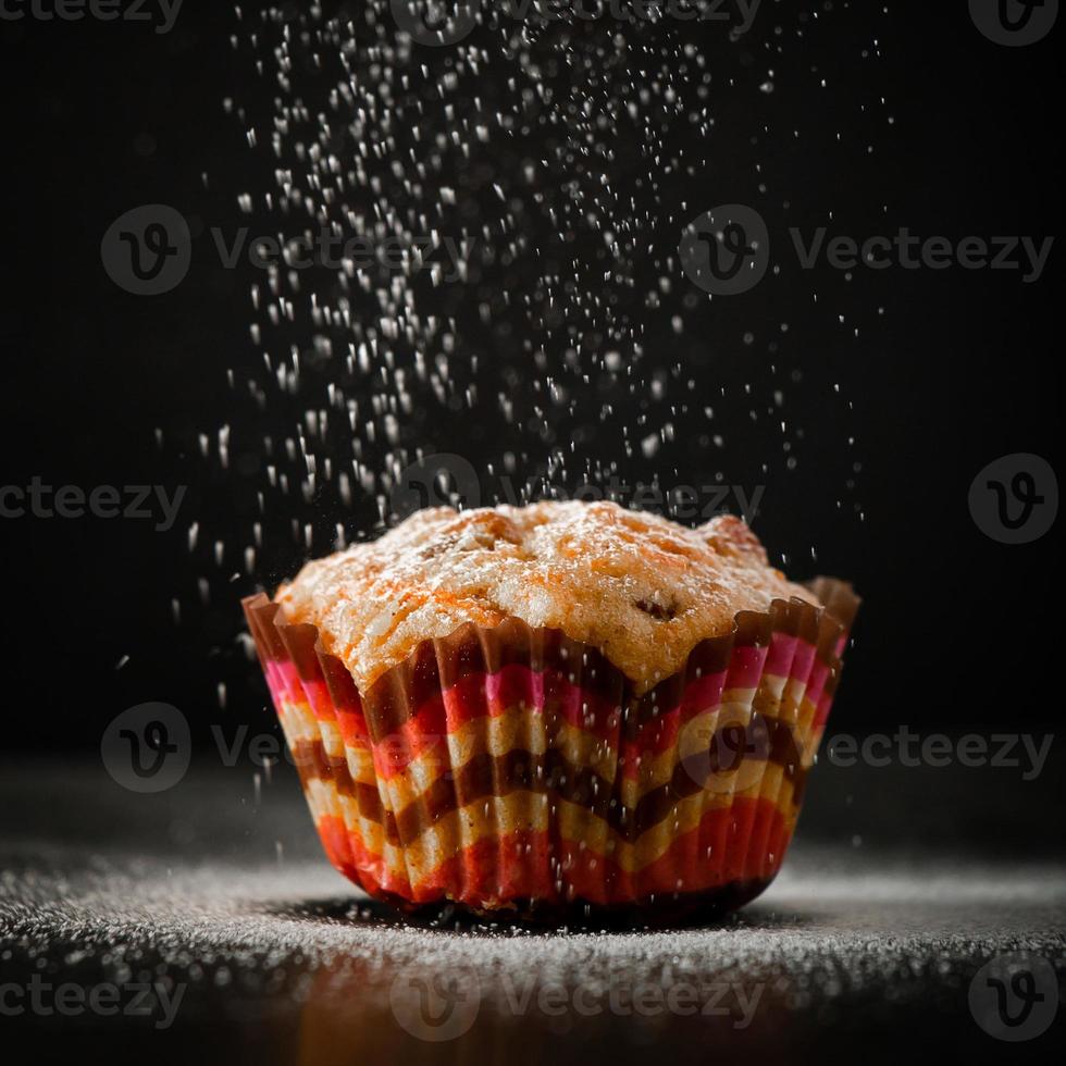 Muffin in icing sugar on a black background photo