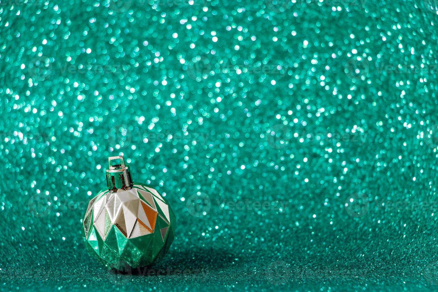 Silver Christmas ball on shiny green background. New Year concept photo