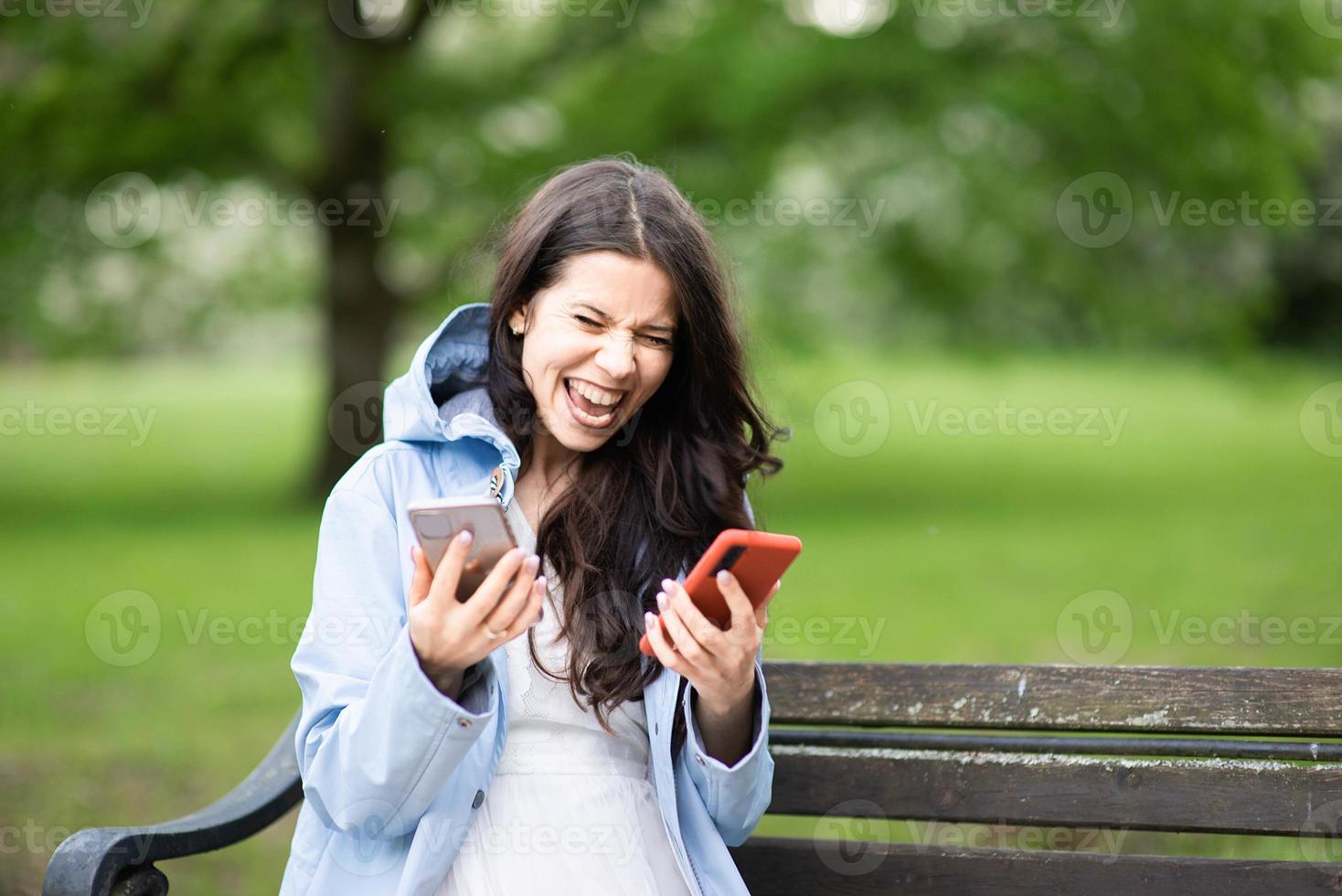 mujer joven morena usa dos teléfonos móviles al mismo tiempo foto