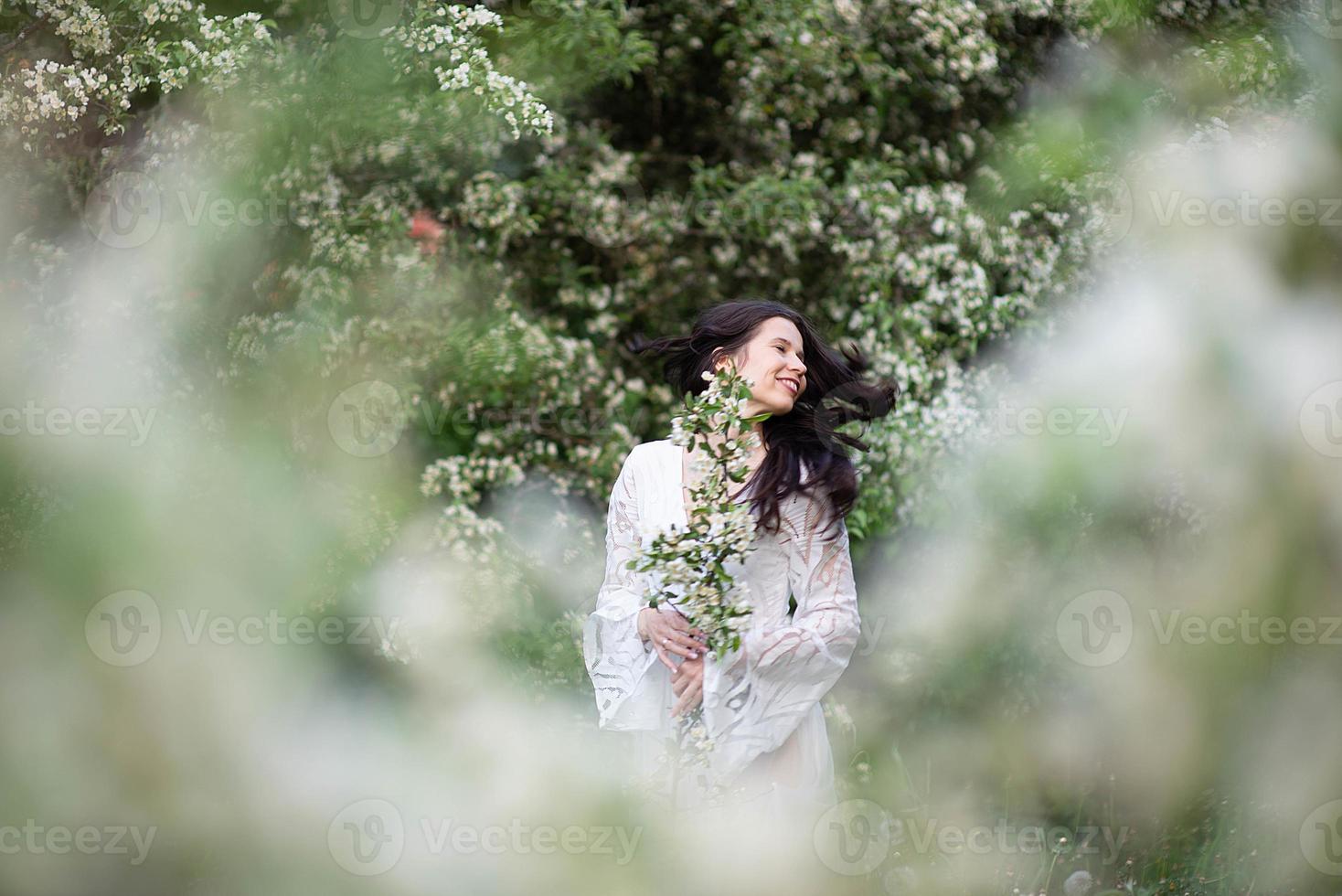 Portrait of a beautiful young woman in the park in blooming branches photo