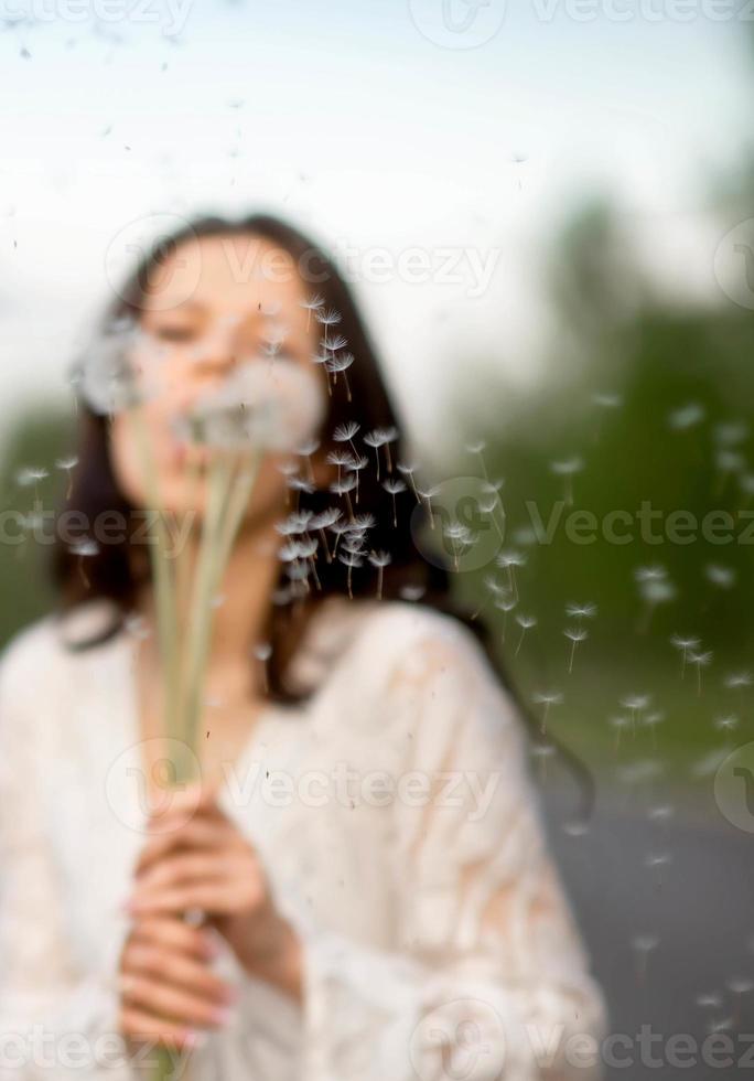 Portrait of young brunette woman with dandelion on rural asphalt road photo