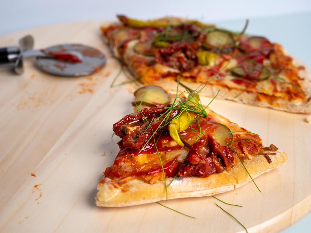 Pizza vegetariana las dos últimas piezas, sobre una mesa de madera, fondo claro foto