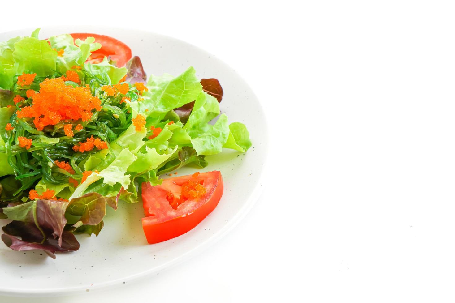 Ensalada de verduras con algas japonesas y huevos de camarón aislado sobre fondo blanco. foto