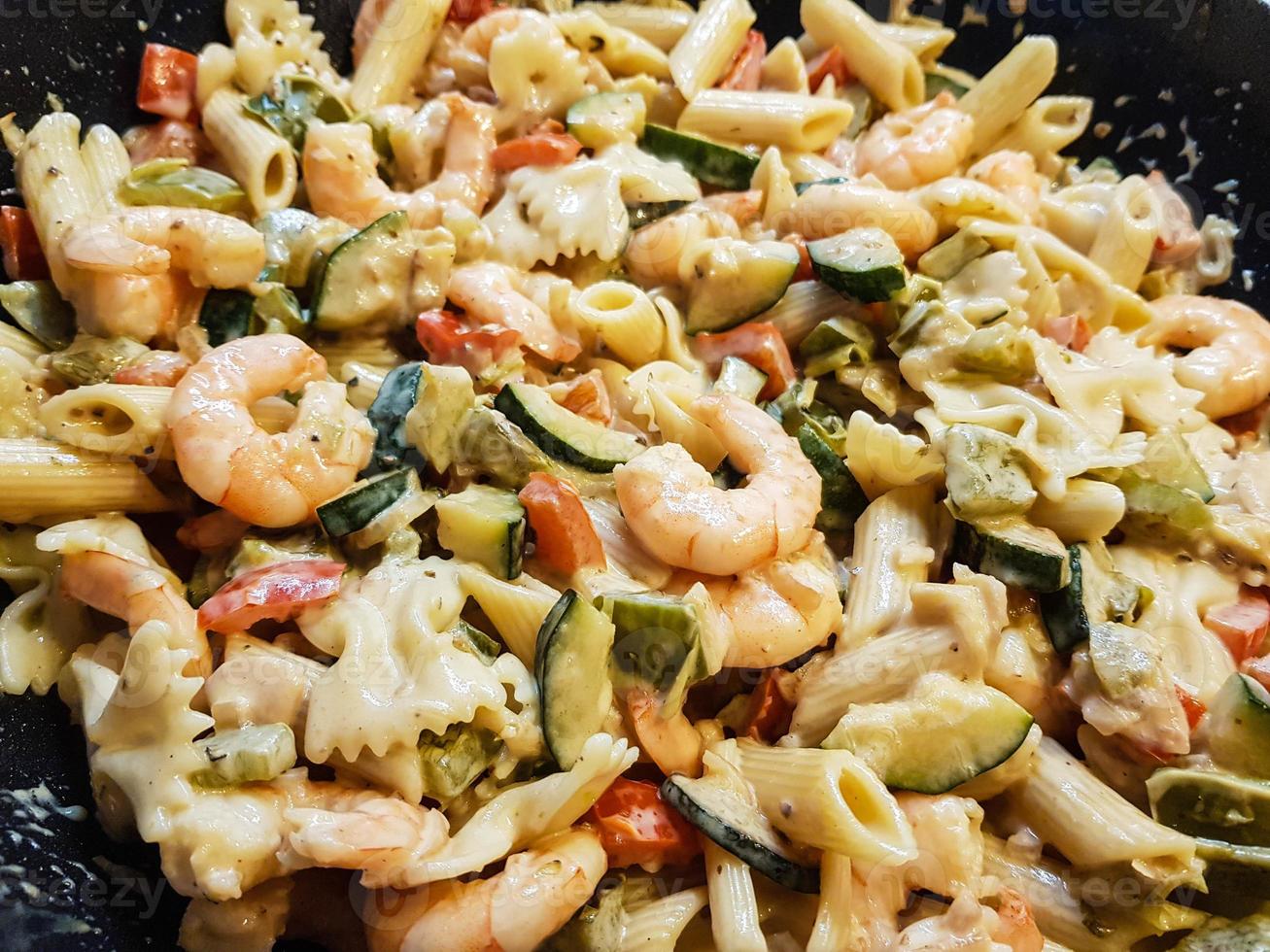 Sartén de fideos de colores con verduras y gambas tigre blancas foto