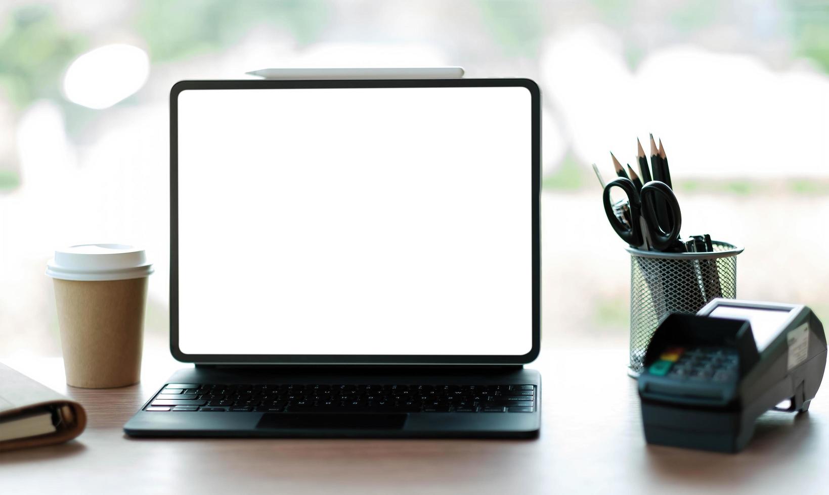 Laptop blank screen with EDC machine on a table in a coffee shop photo