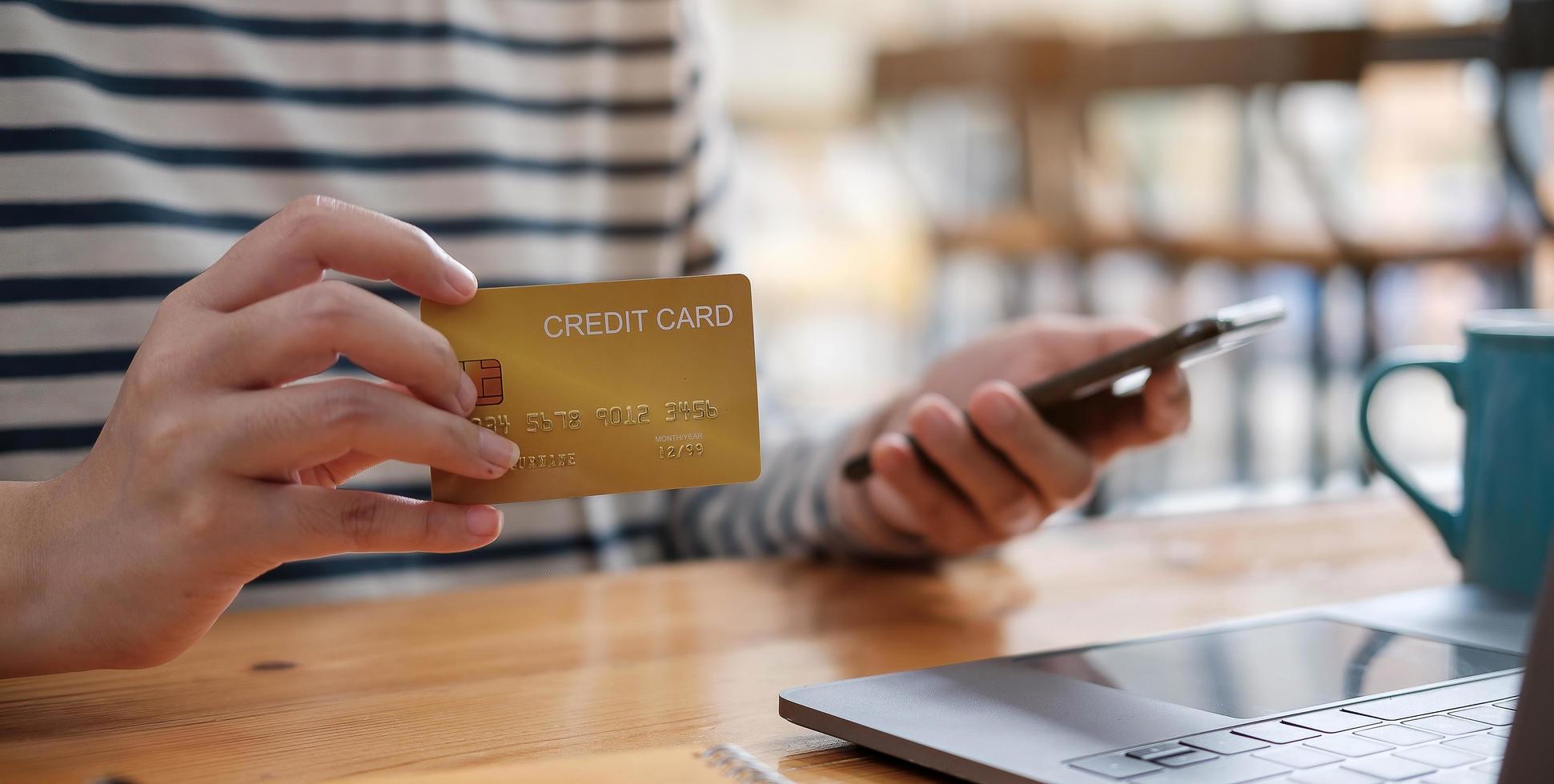 Young woman holding credit card and using smartphone photo