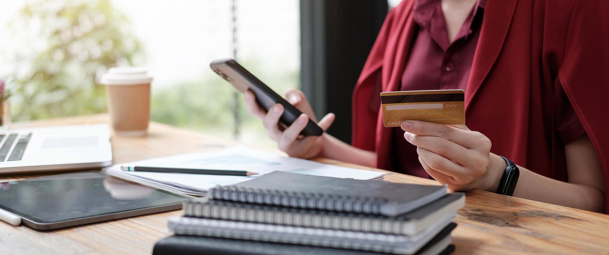 Young woman holding credit card and using smartphone photo