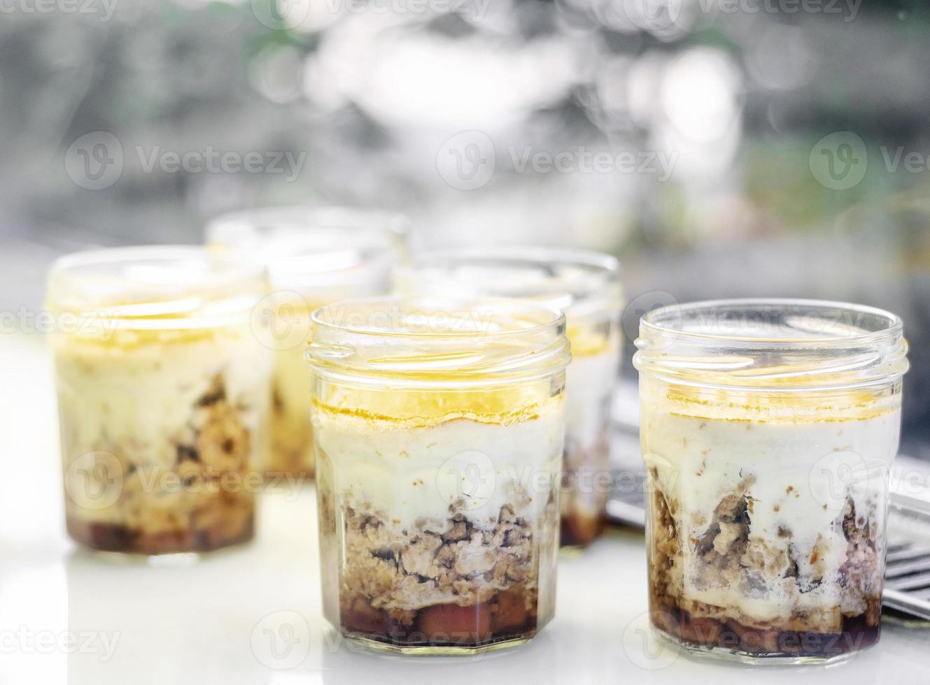 Organic apple and coconut vegan cheesecake dessert in a glass jam jar in cafe display photo