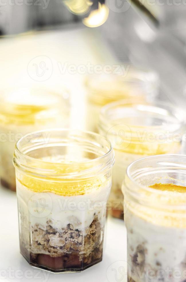 Organic apple and coconut vegan cheesecake dessert in a glass jam jar in cafe display photo